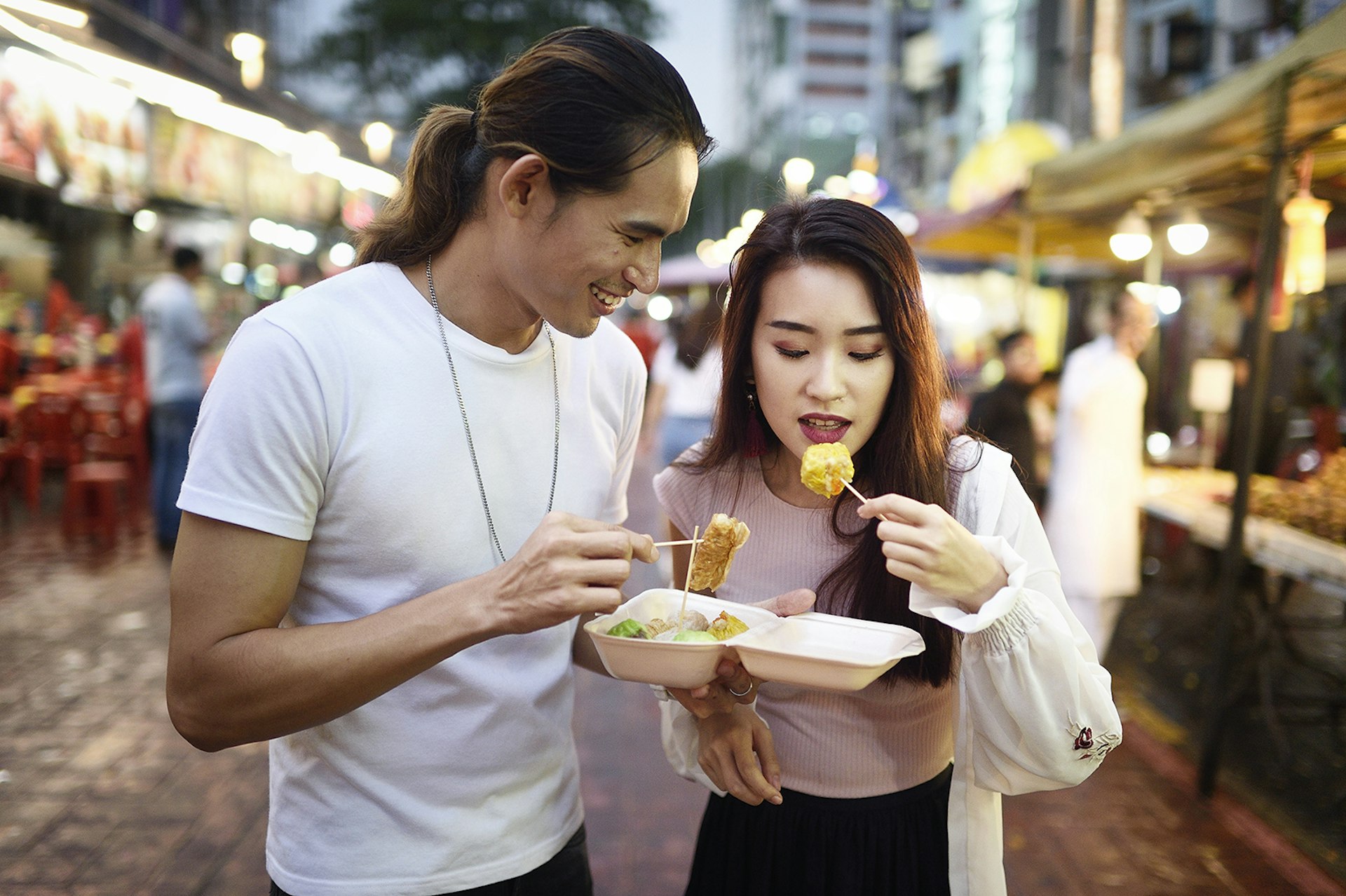 A couple eating some street food in a market