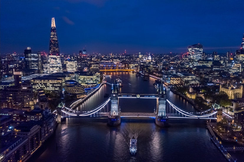 A night-time aerial view of London's skyline shoiwng Tower Bridge and the Shard.