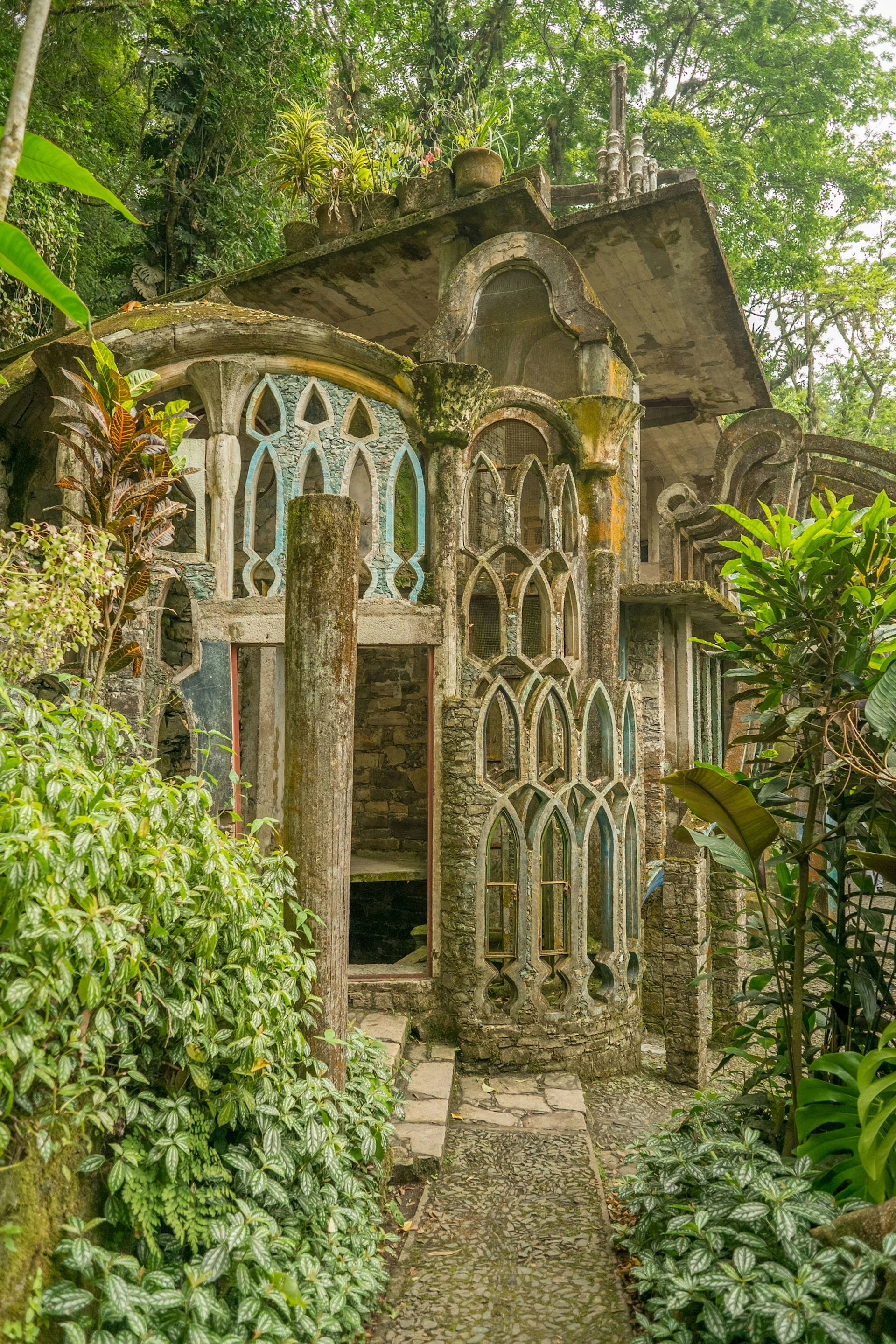Stone arches filled with glass surrounded by jungle plants
