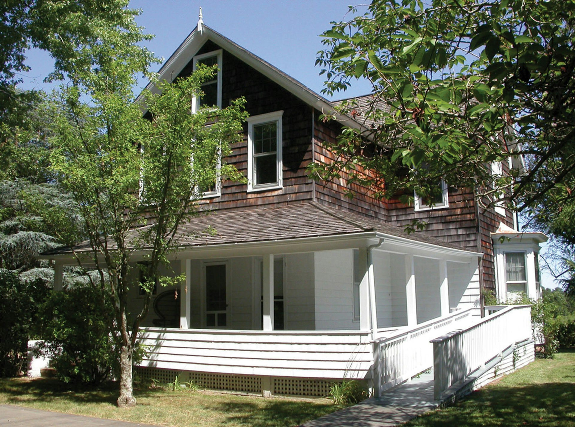 An attractive wooden house, partially obscured by trees, with white-painted decking, the former residence of Jackson Pollock and Lee Krasner, in East Hampton