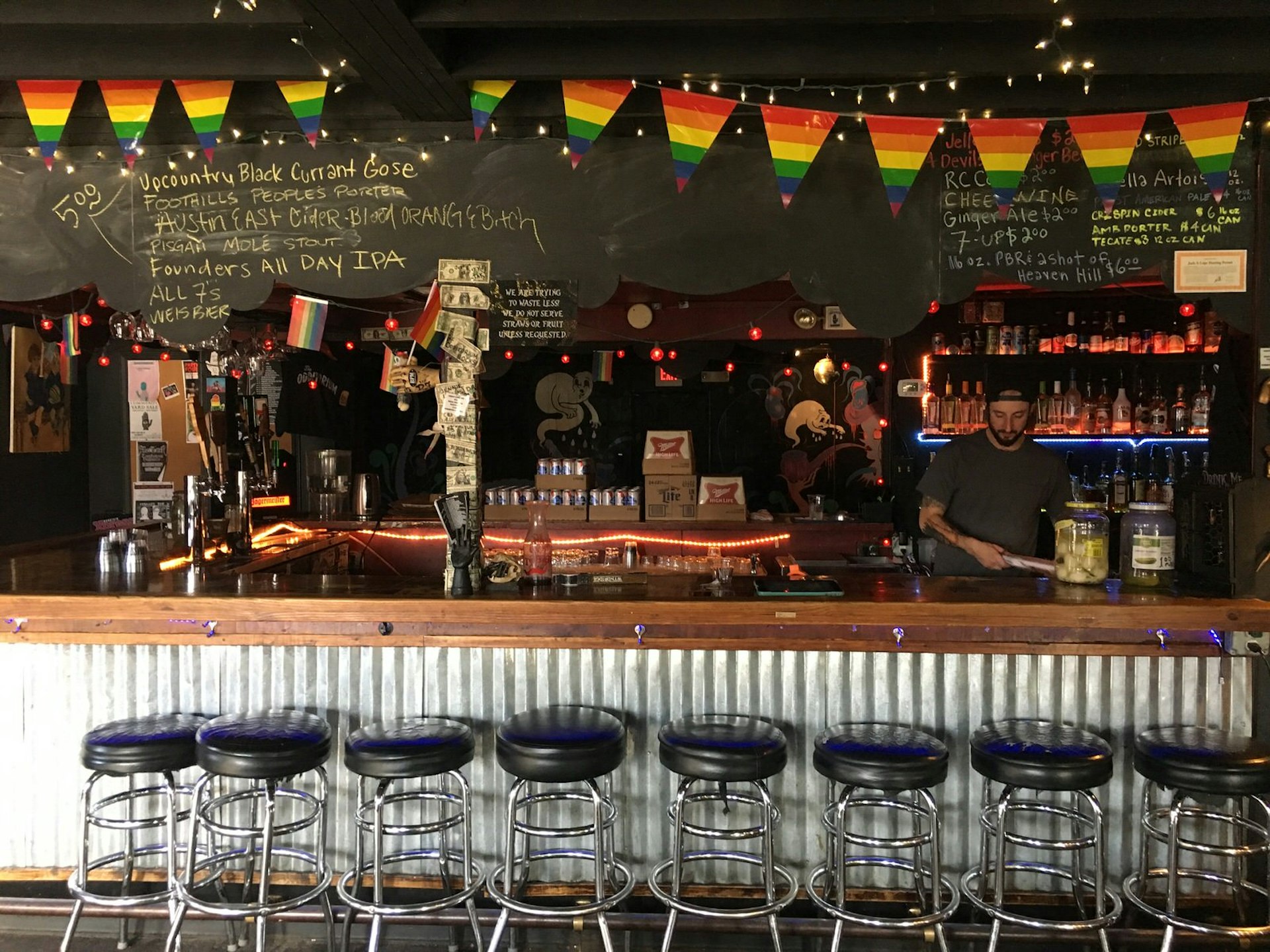 Beneath rainbow-coloured bunting and hand-written chalkboard bar menus, a bartender in a baseball cap and dark shirt busies himself getting ready for patrons to arrive at Asheville music venue The Odditorium