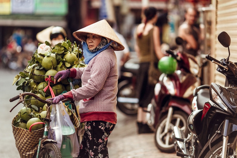 A Vietnamese woman in a conical hat sells fresh green coconuts on the street of Ho Chi Minh city in Vietnam,