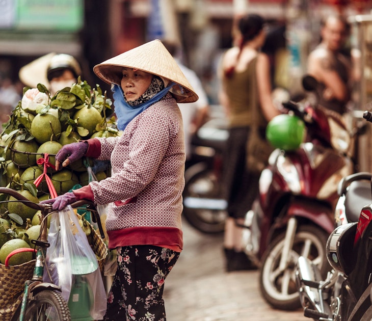 A Vietnamese woman in a conical hat sells fresh green coconuts on the street of Ho Chi Minh city in Vietnam,