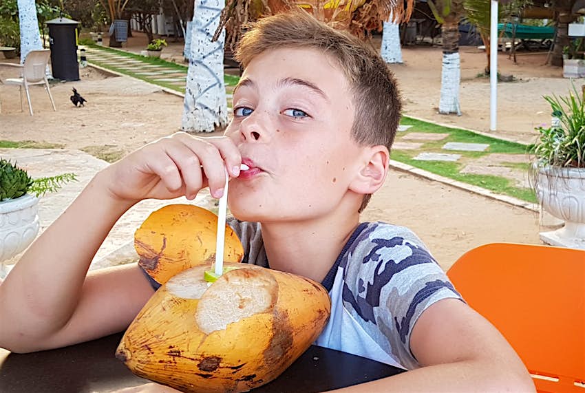 Boy drinking from a fresh coconut