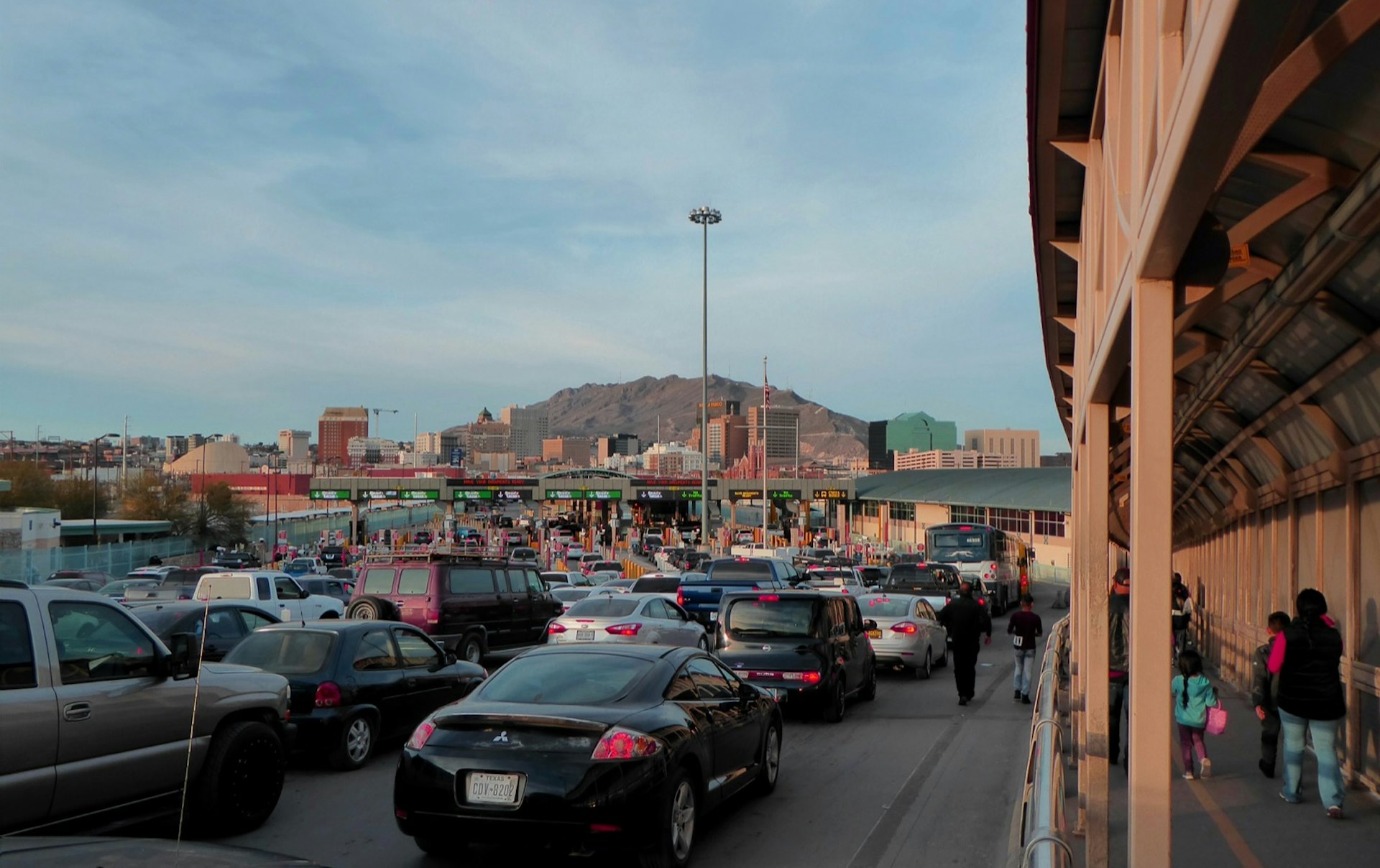 Several lines of cars are immobile as people walk through a port of entry on the US-Mexico border in El Paso, Texas