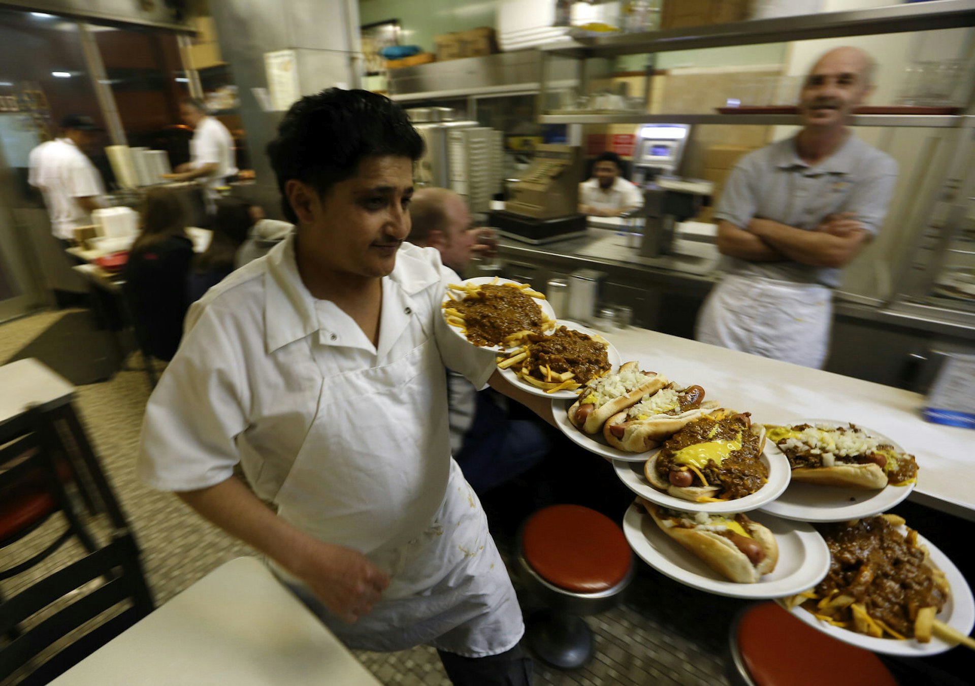 A waiter delivering coney dogs and chili fries at Lafayette Coney Island in Detroit