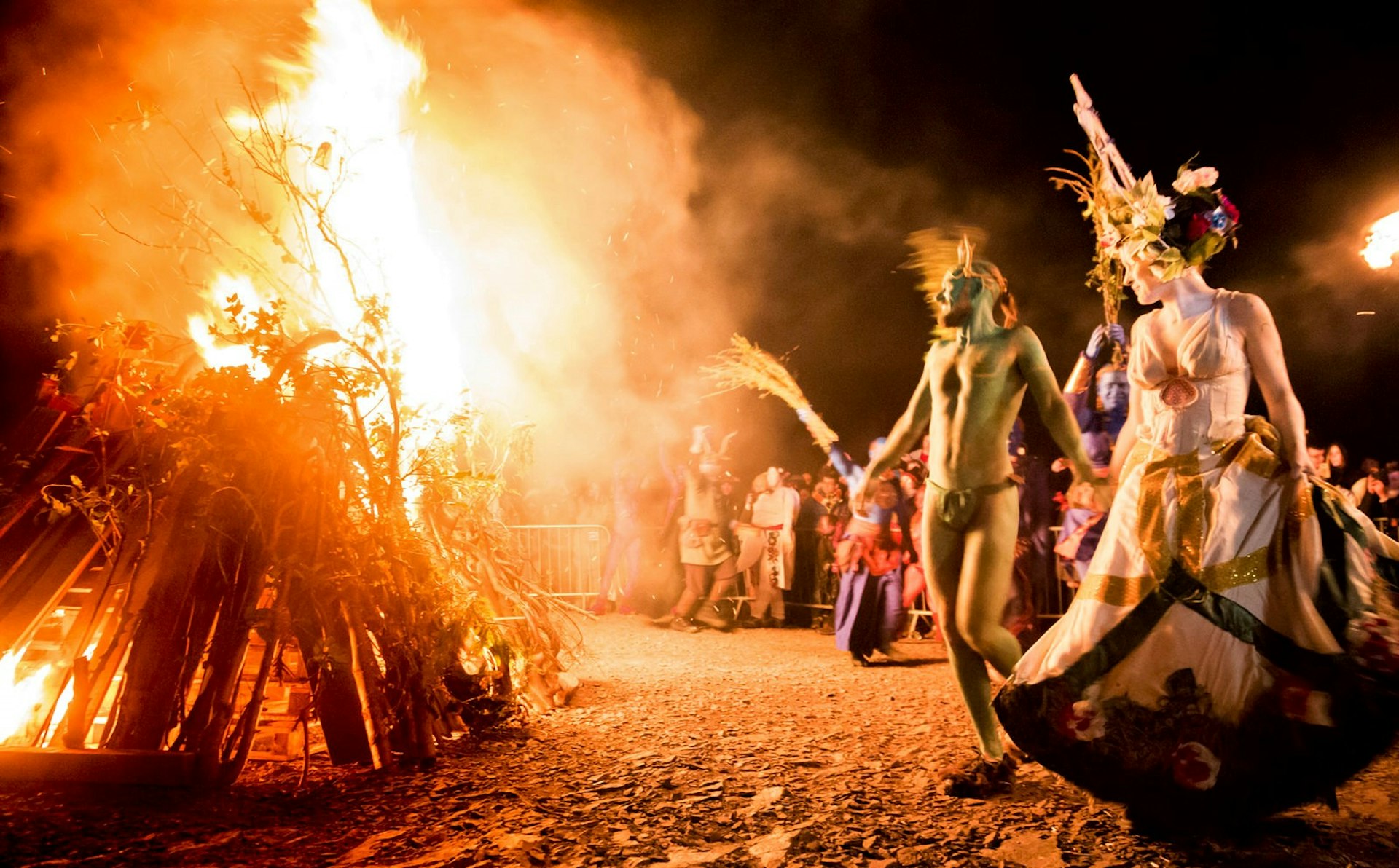 Costumed characters celebrate Beltane in Edinburgh by a huge fire.