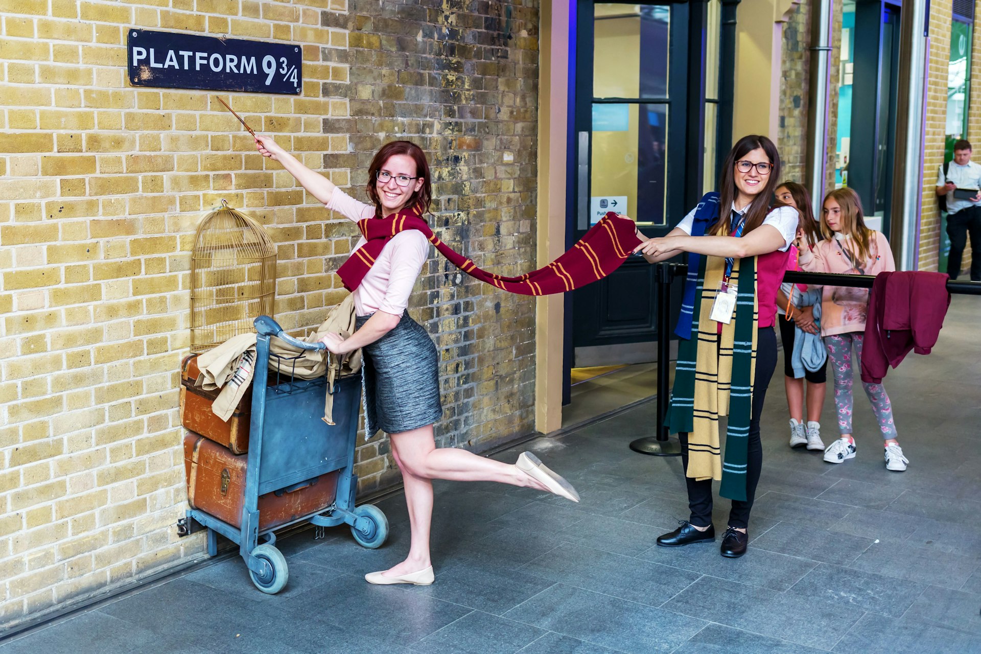 A woman pretends to walk through the wall of Platform 9¾ at King's Cross Station