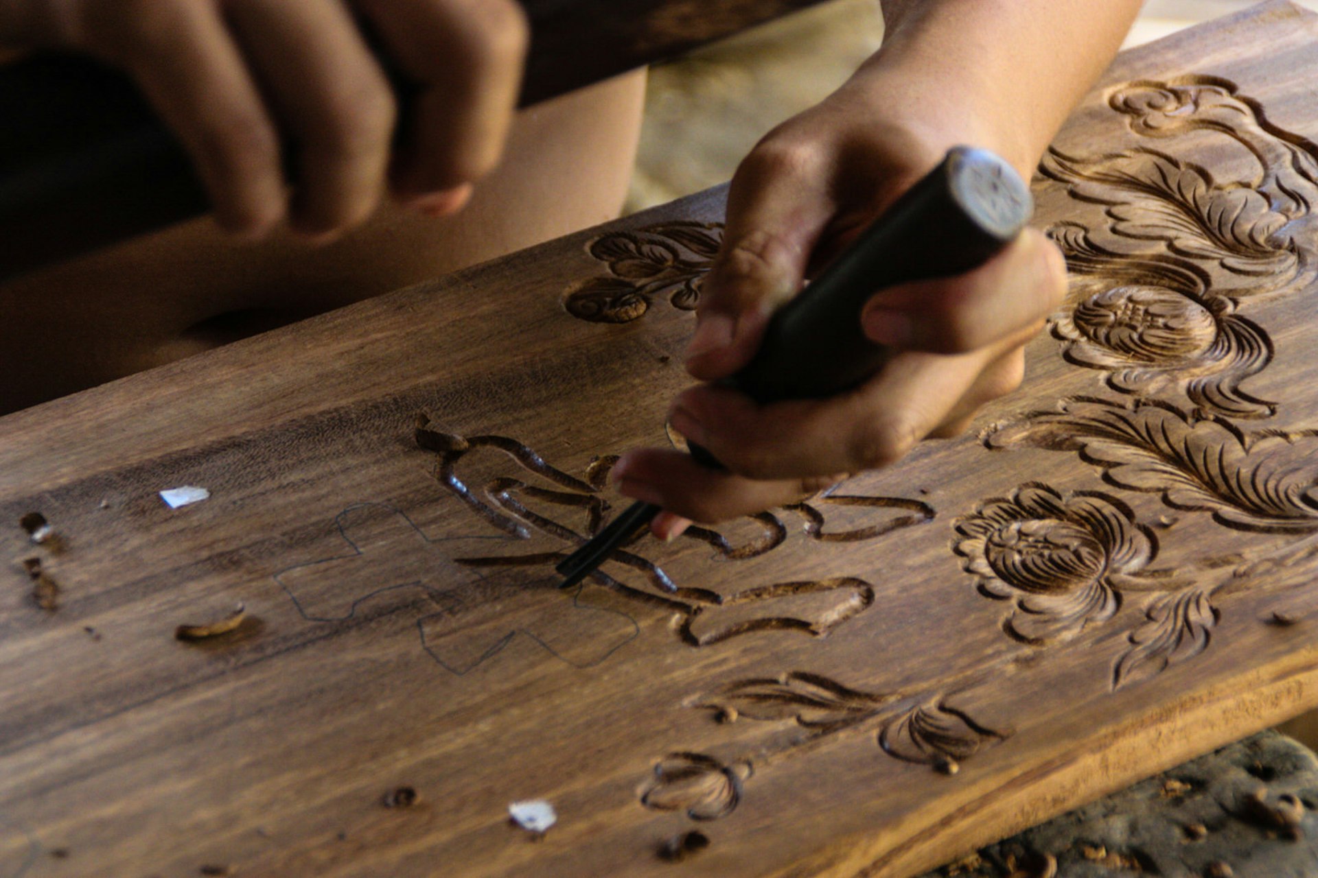 A man works on a wood carving to be inlaid with mother-of-pearl at Kim Bong
