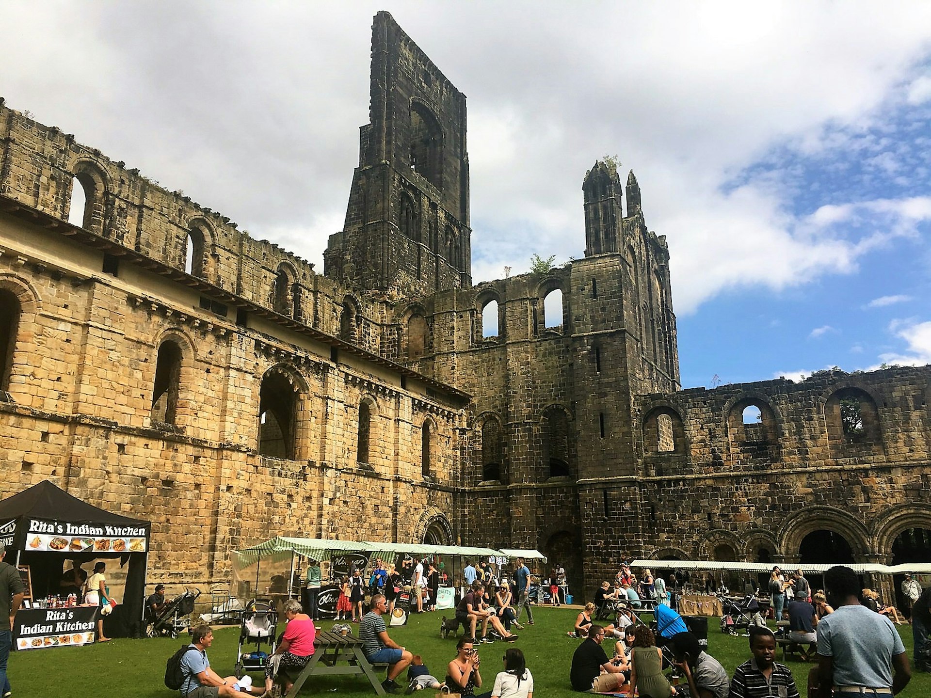 People eating from food stalls in the ruins of Kirkstall Abbey.