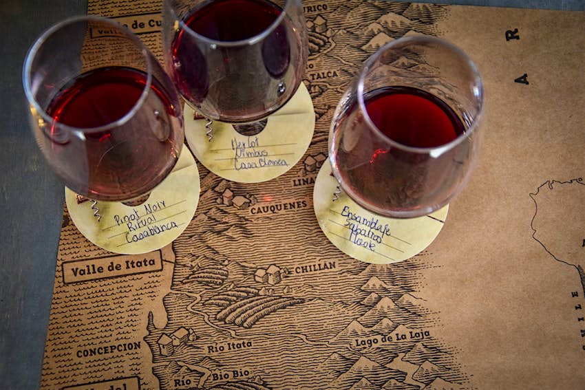 An overhead shot of three classes of red wine placed on a map of Chile 