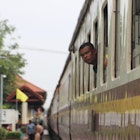 A man peeps his head out of a train window en route to Bangkok