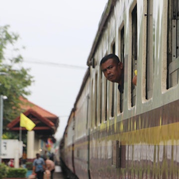 A man peeps his head out of a train window en route to Bangkok