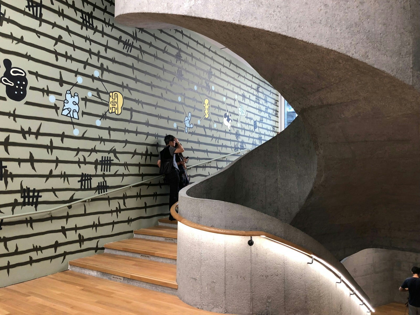 Contemporary art gallery with brutalist spiral staircase and mural painting on the wall