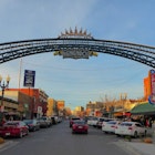 A city street, with shops along each side, is dominated by a colorful archway in the foreground that welcomes visitors to El Paso, Texas
