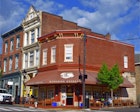 A corner shop in red brick with a maroon awning bearing the words "Hyperion Espresso" on a sunny day in Virginia