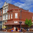 A corner shop in red brick with a maroon awning bearing the words "Hyperion Espresso" on a sunny day in Virginia