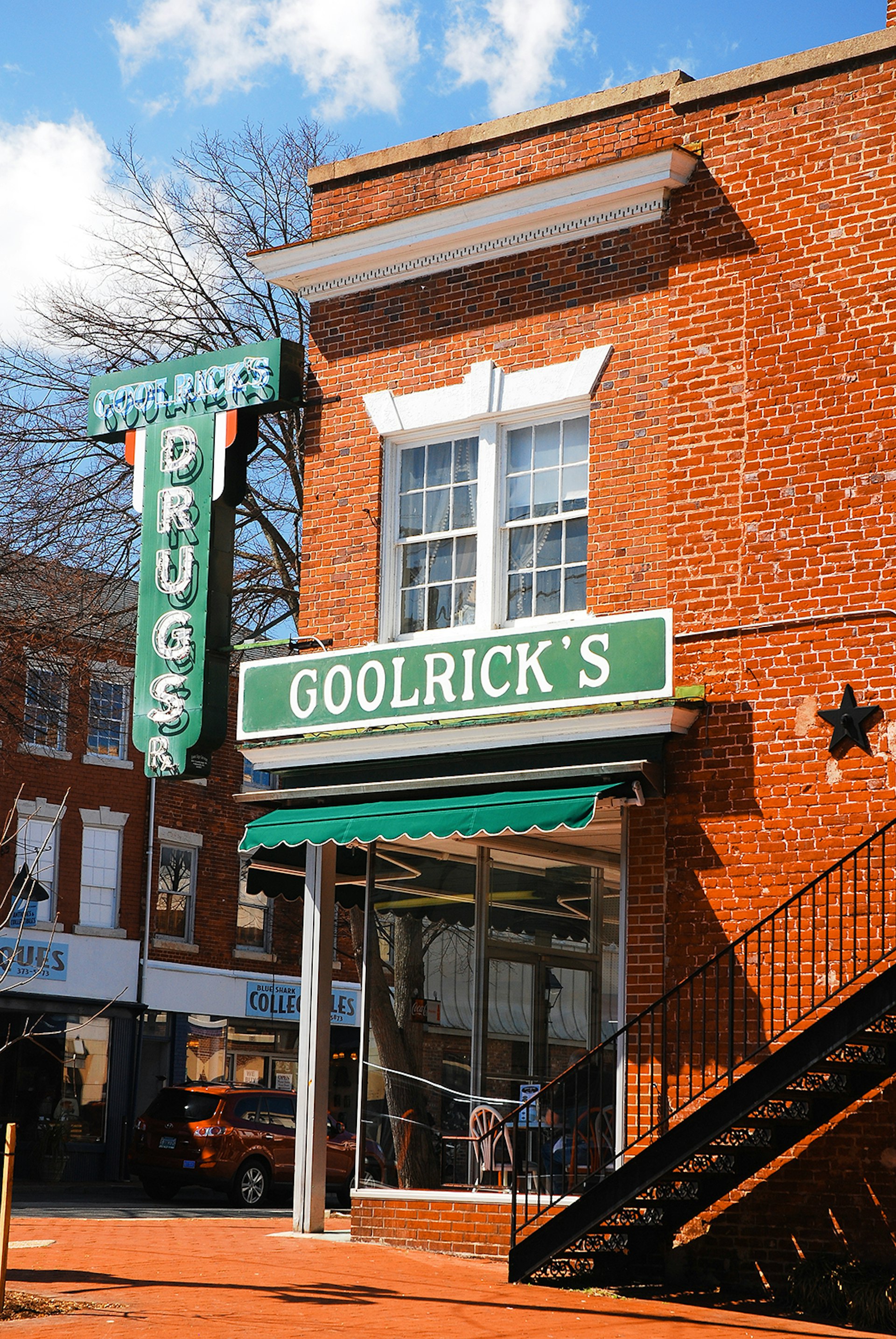 red brick facade and green neon sign reading 'Goolrick's Pharmacy'