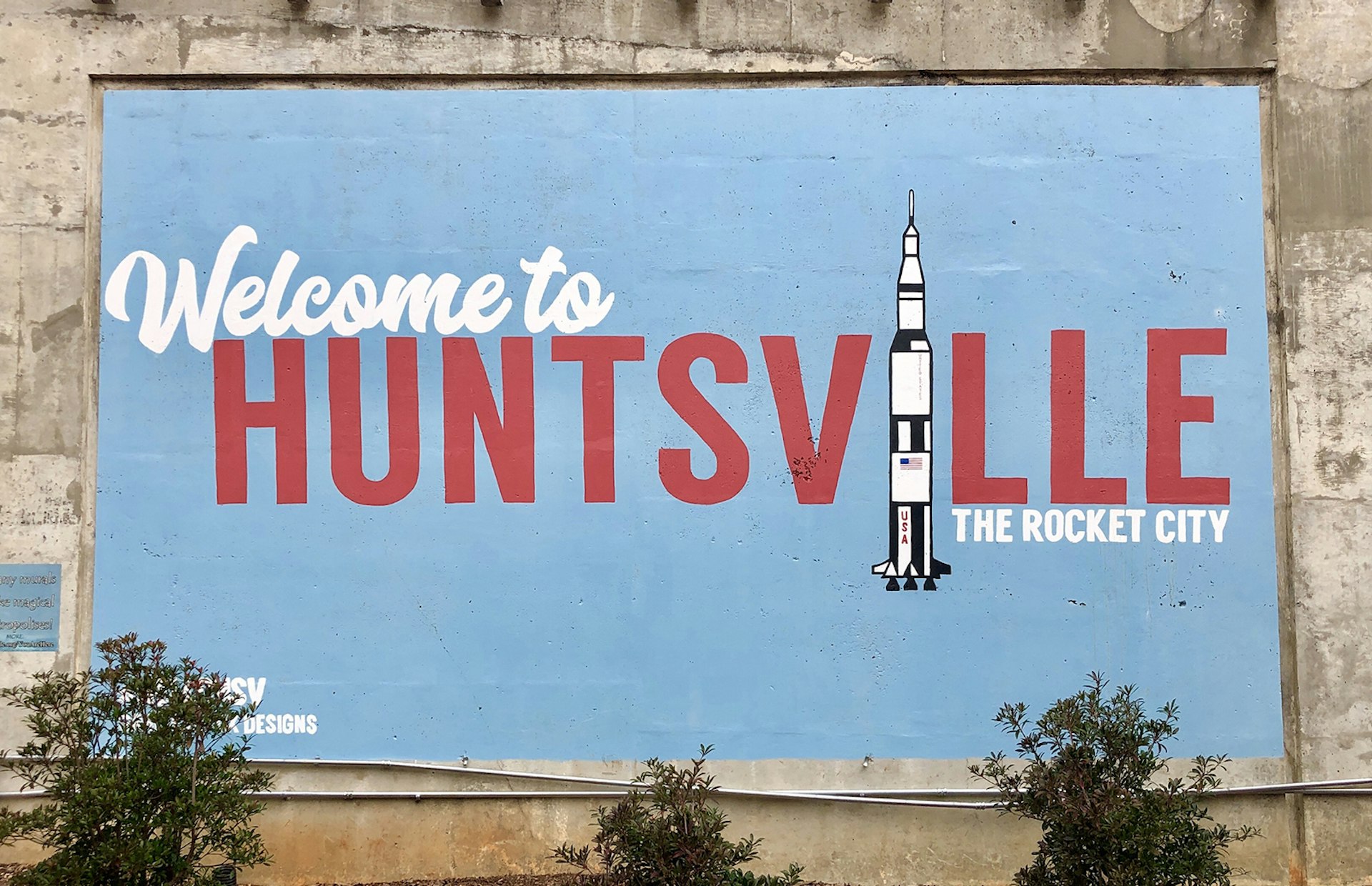 Mural with blue background that includes the text "welcome to Huntsville." The "I" in Huntsville is a rocket ship.