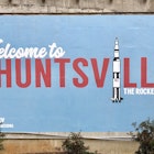 mural with blue background that includes the text "welcome to Huntsville." The "I" in Huntsville is a rocket ship