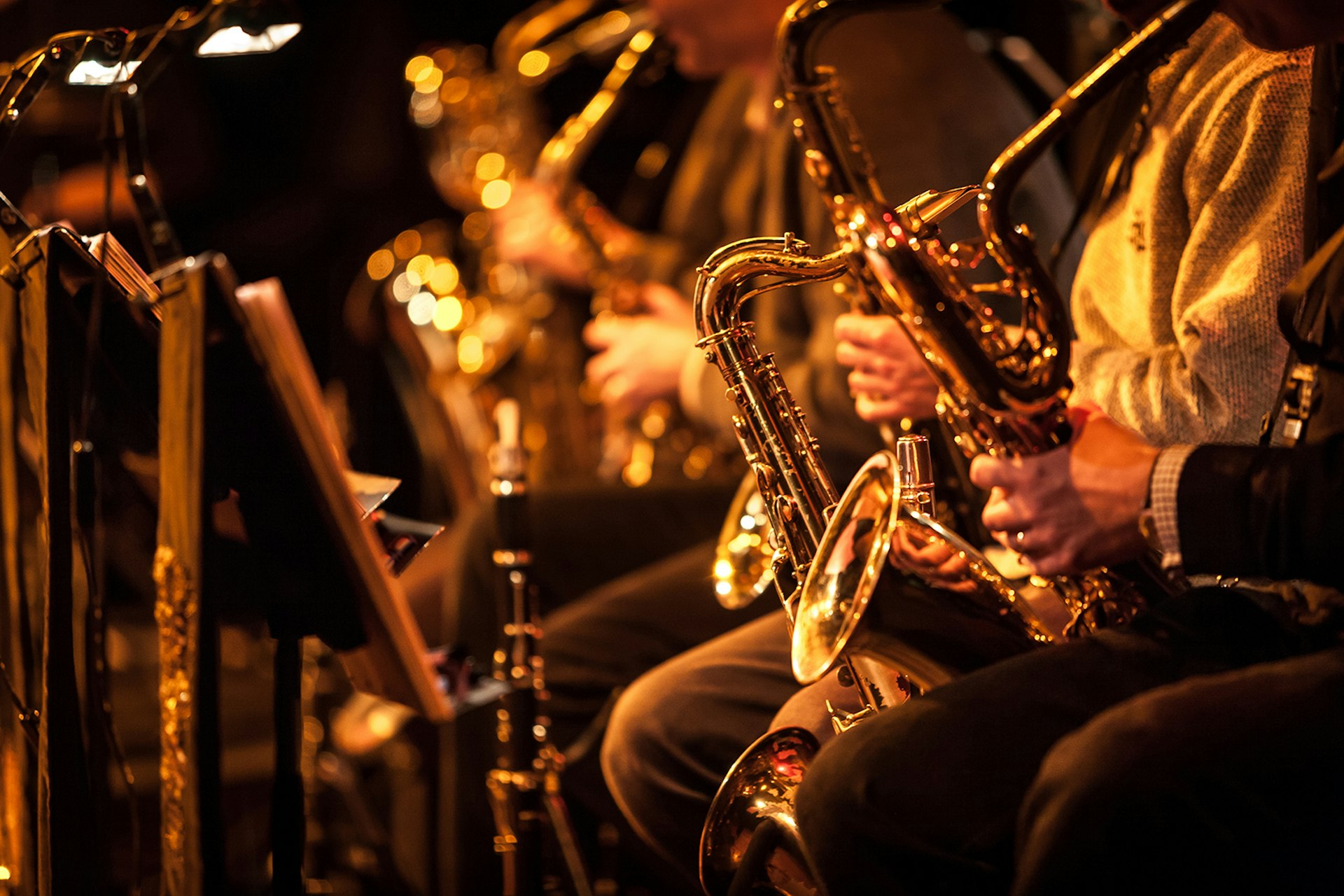 Candid view of a row of saxophone players in mid performance during a big band rehearsal.