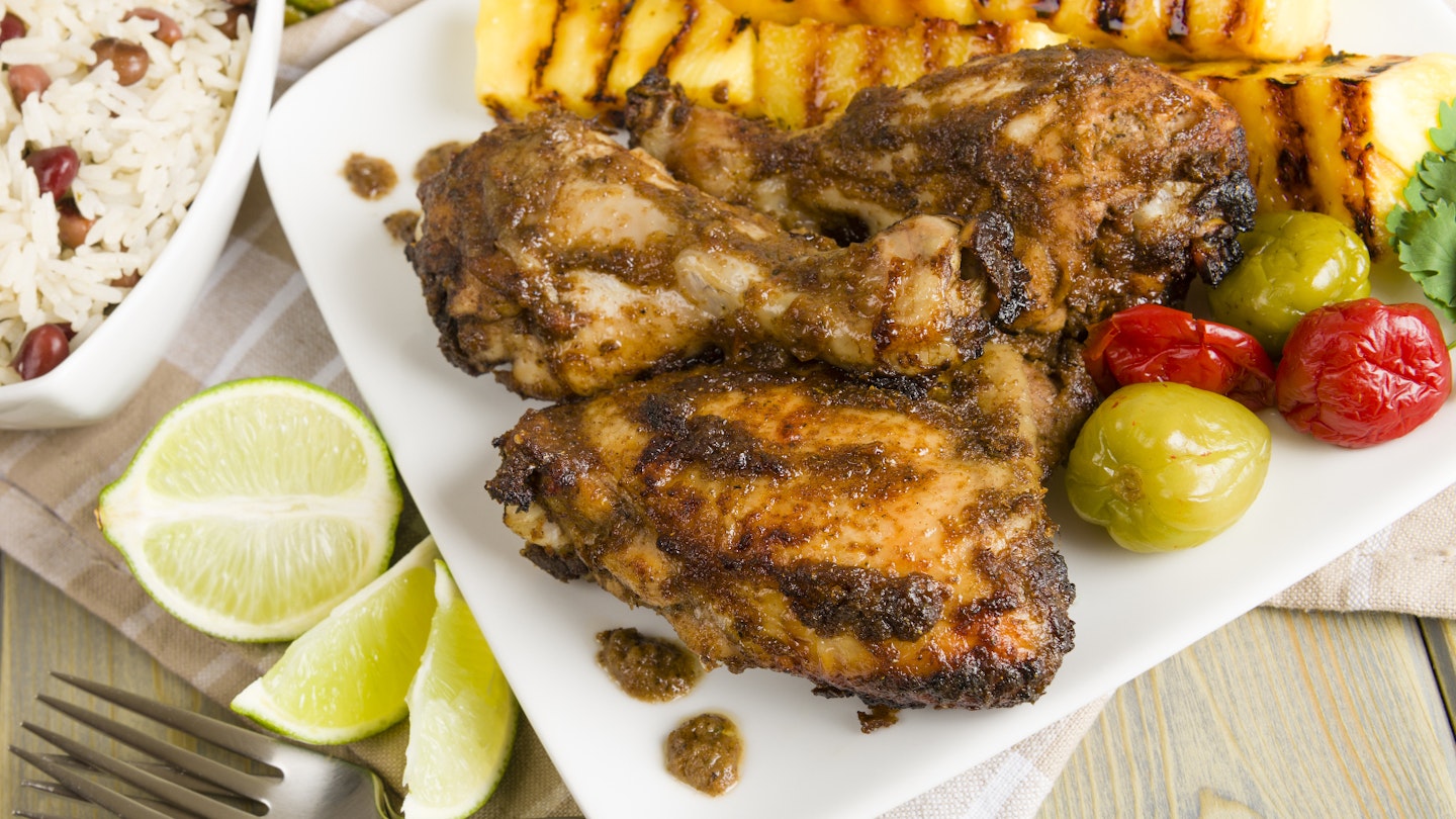 Jamaican jerk chicken served with grilled pineapple, rice and peas and lime wedges © Paul Brighton / Shutterstock