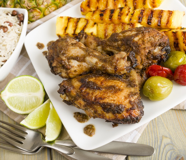 Jamaican jerk chicken served with grilled pineapple, rice and peas and lime wedges © Paul Brighton / Shutterstock