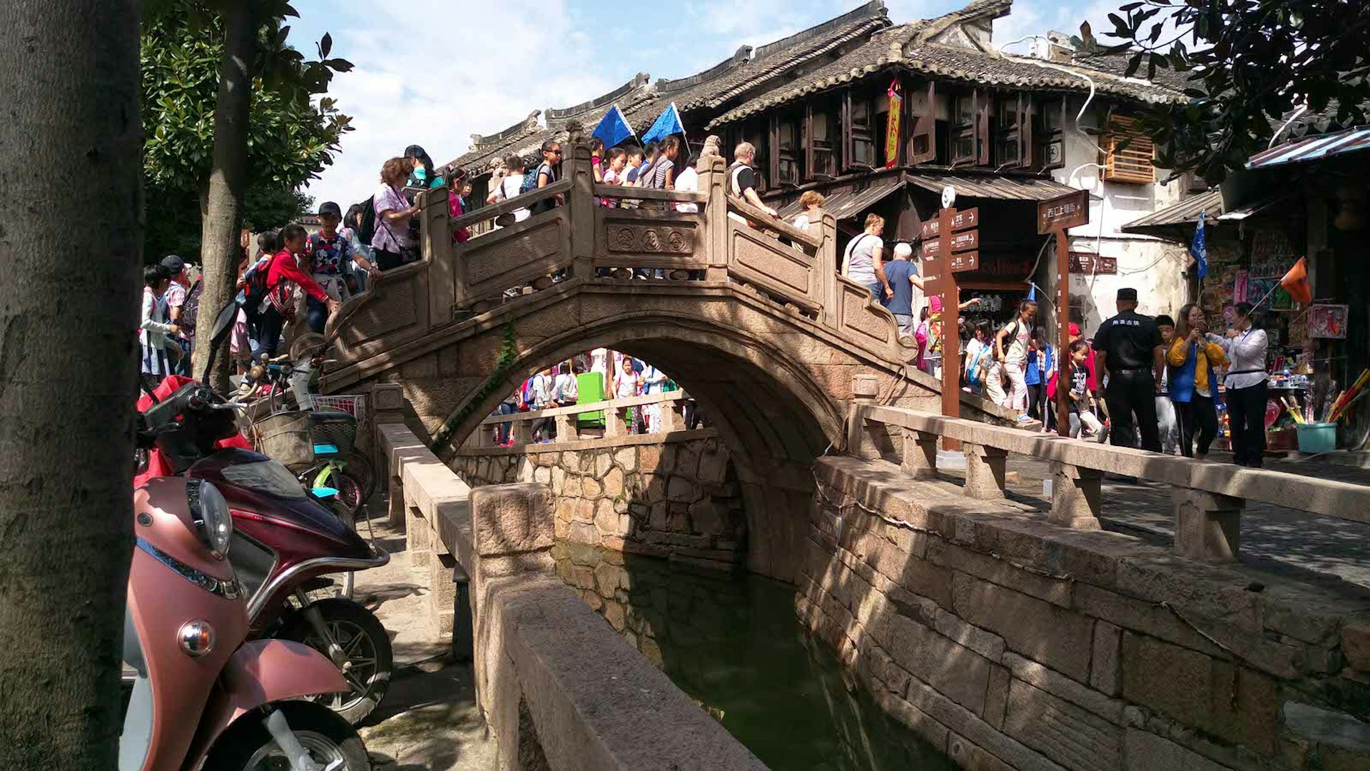 Tourists walking over an ancient bridge in Luzhi