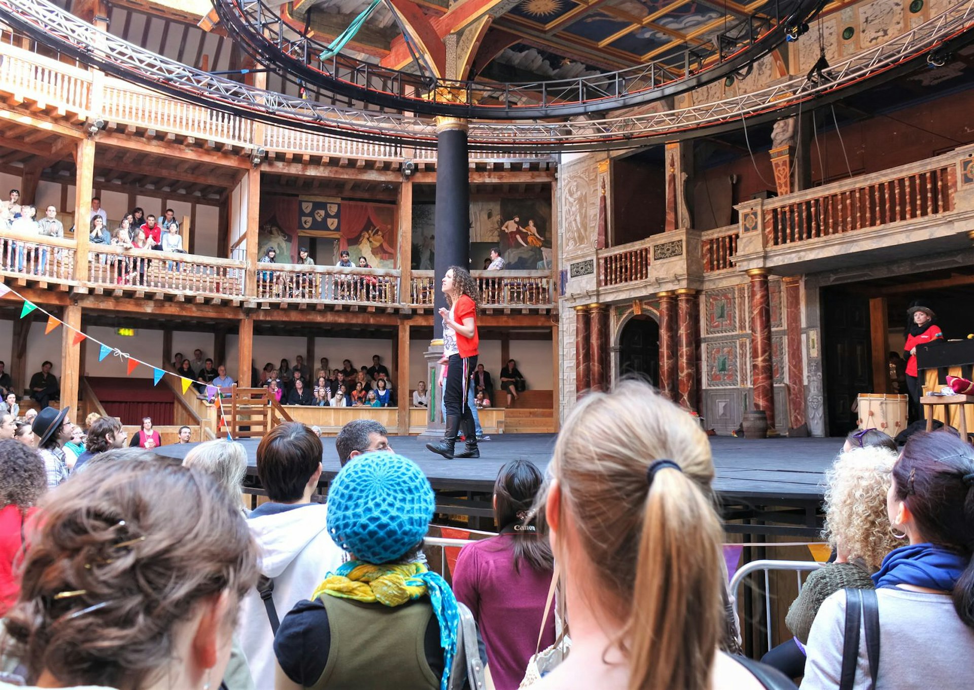 The audience watches a performer on the stage at Shakespeare's Globe, London
