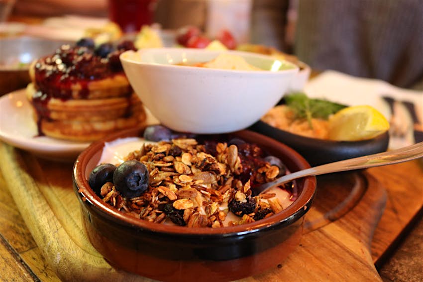 Bowls and plates of brunch foods such as granola, fruit and pastries stack on each other at a Copenhagen restaurant.