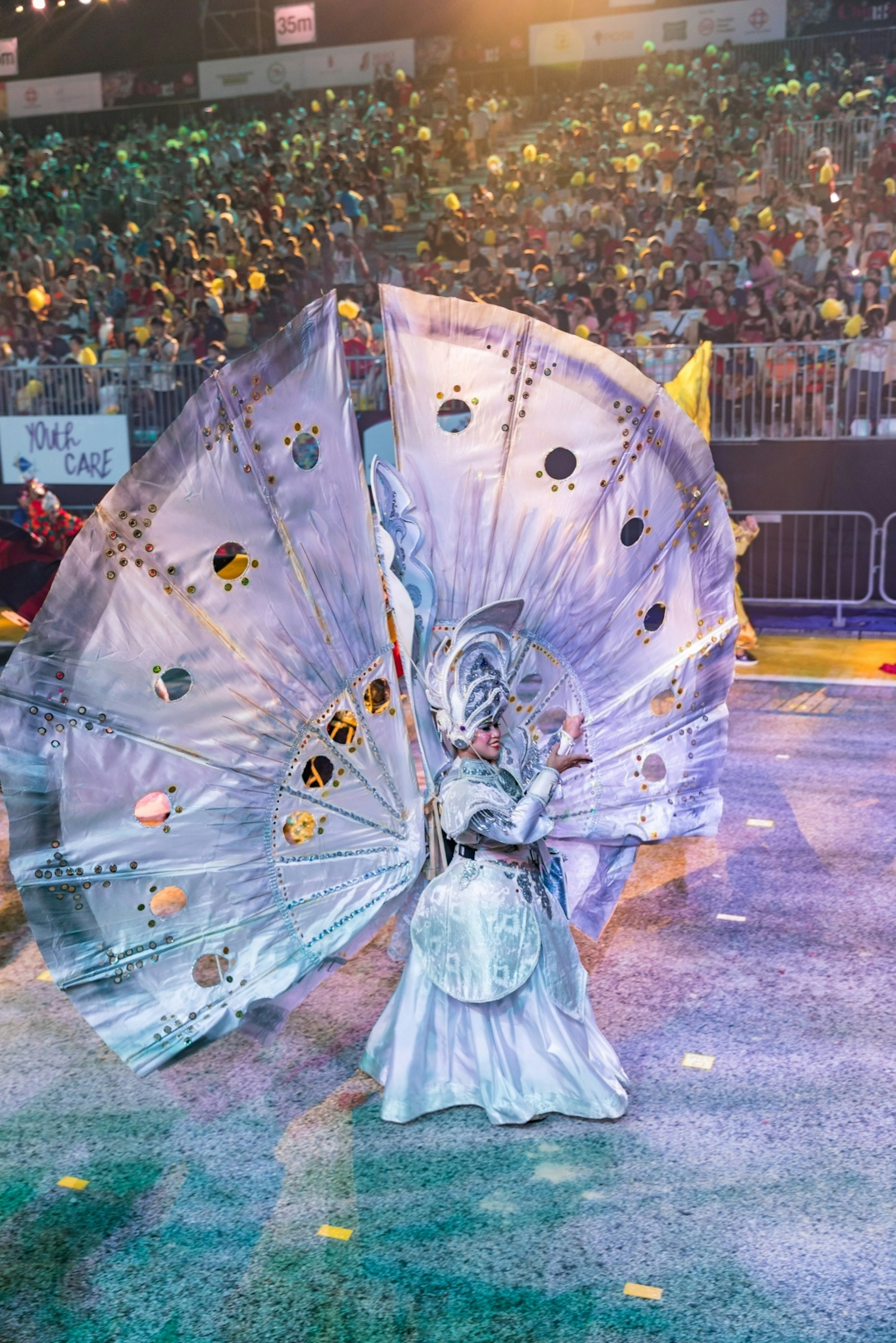 A Chingay Parade performer walks by in an intricate, larger-than-life white ensemble. 