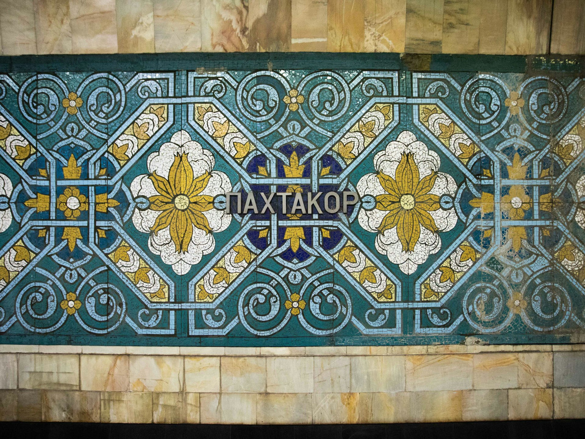 The walls of Pakhtakor station bearing the station name surrounded by ornate blue and green Uzbek mosaics.