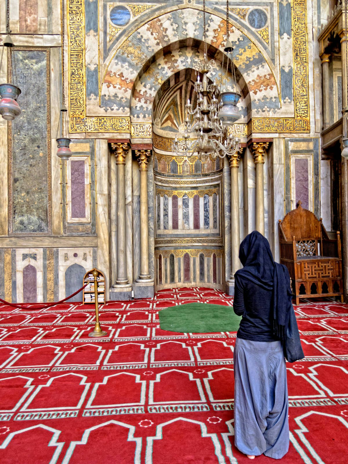 Woman stands in front of the mihrab of the Sultan Hassan Mosque in Cairo, Egypt