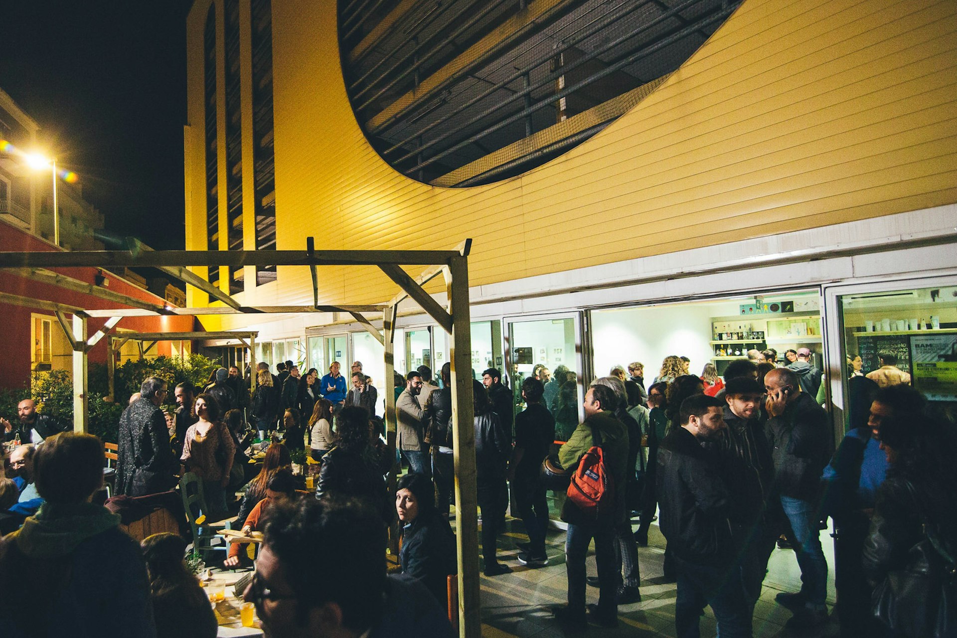 People drinking and chatting at night at the Officina degli Esordi