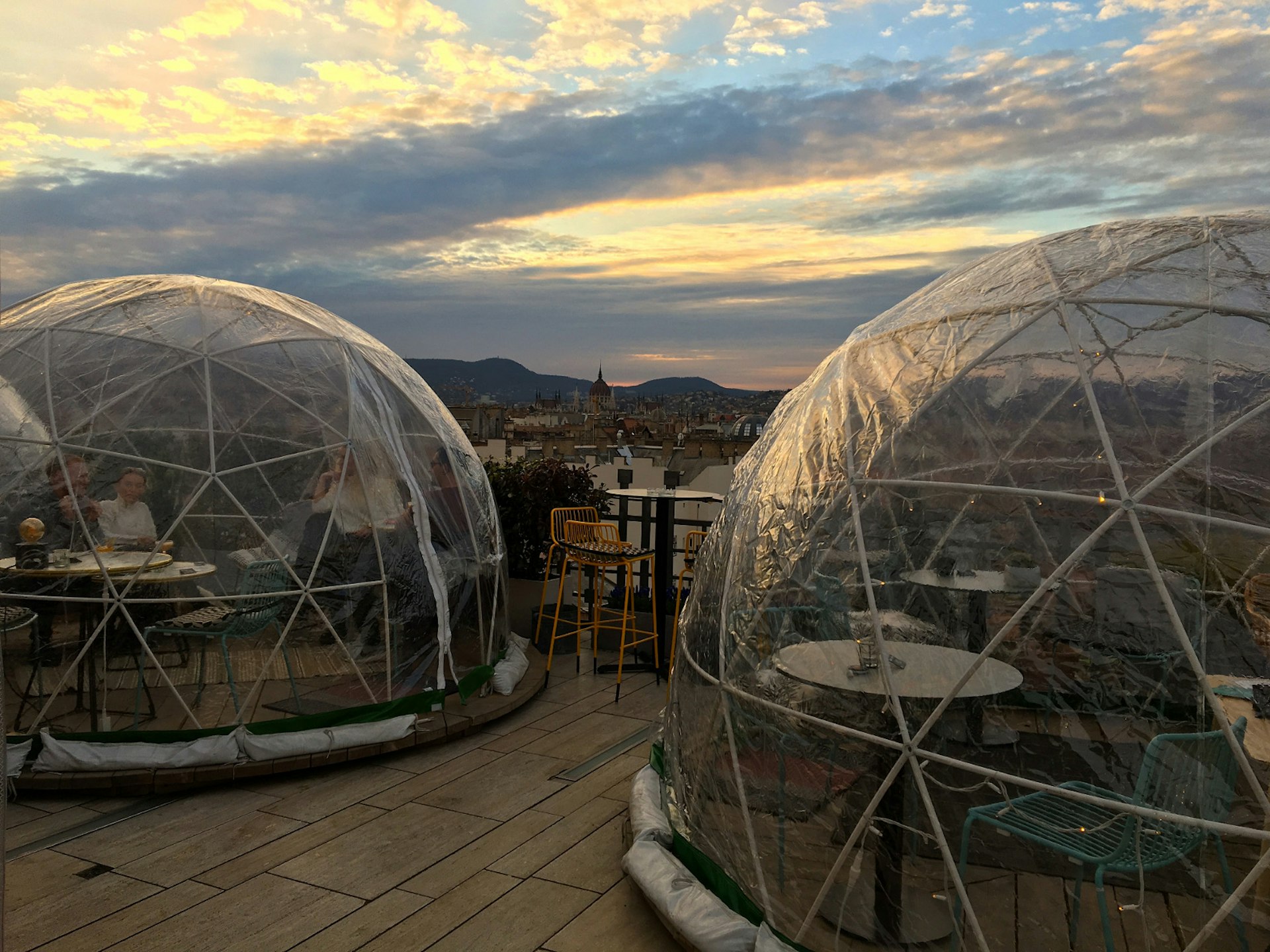 People enjoying the sunset from transparent igloos on the rooftop terrace at 360Bar in Budapest