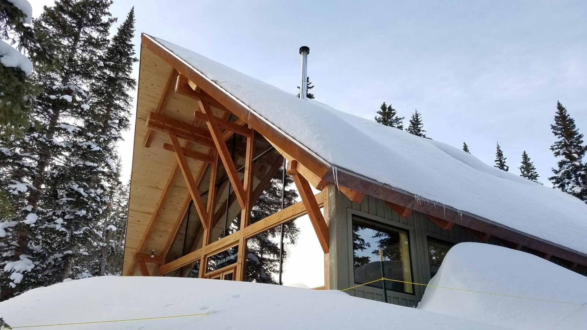 The strong pitch of an A-frame lodge are seen rising over a large snowdrift