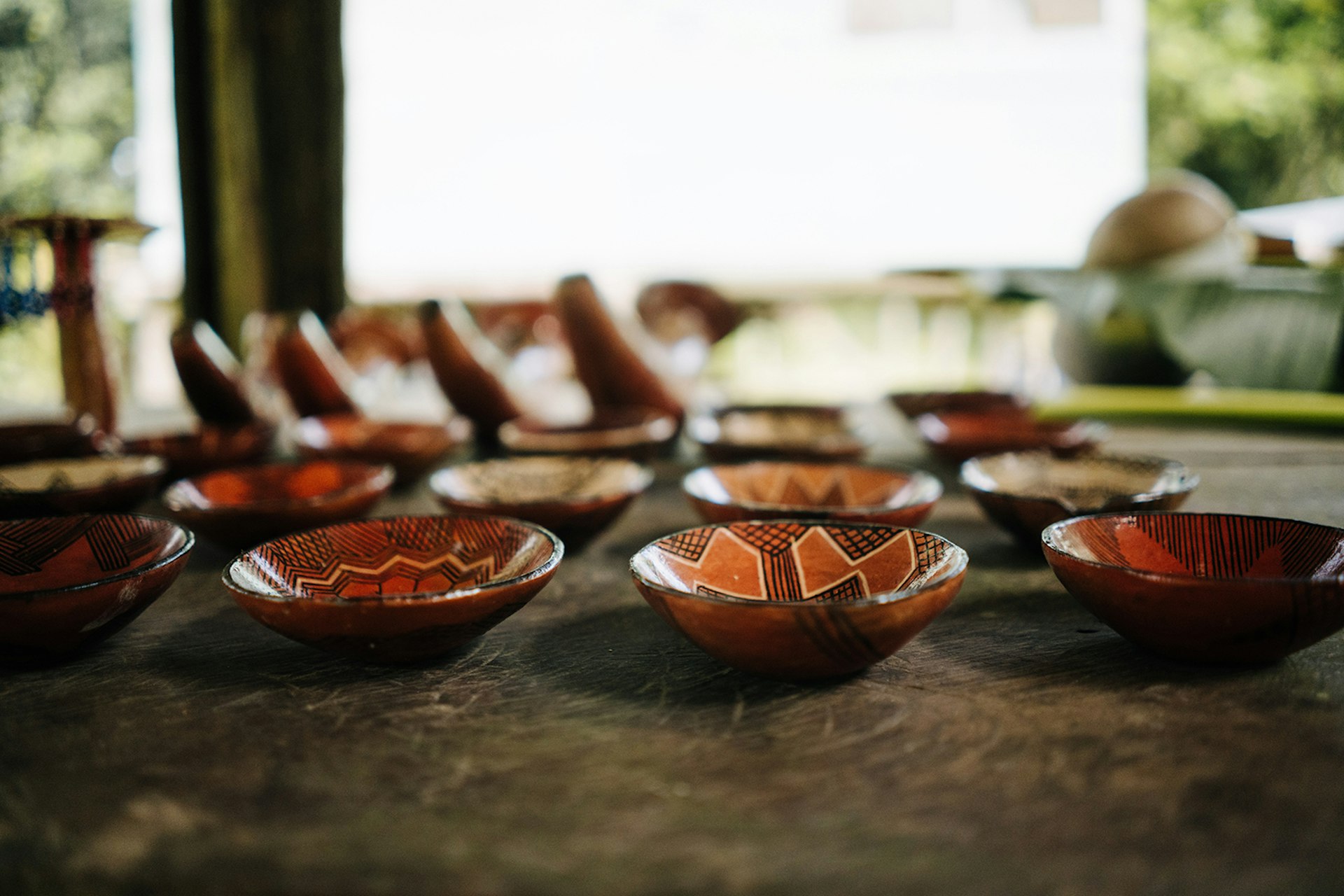 A close up of shallow clay bowls with indigenous designs painted on them
