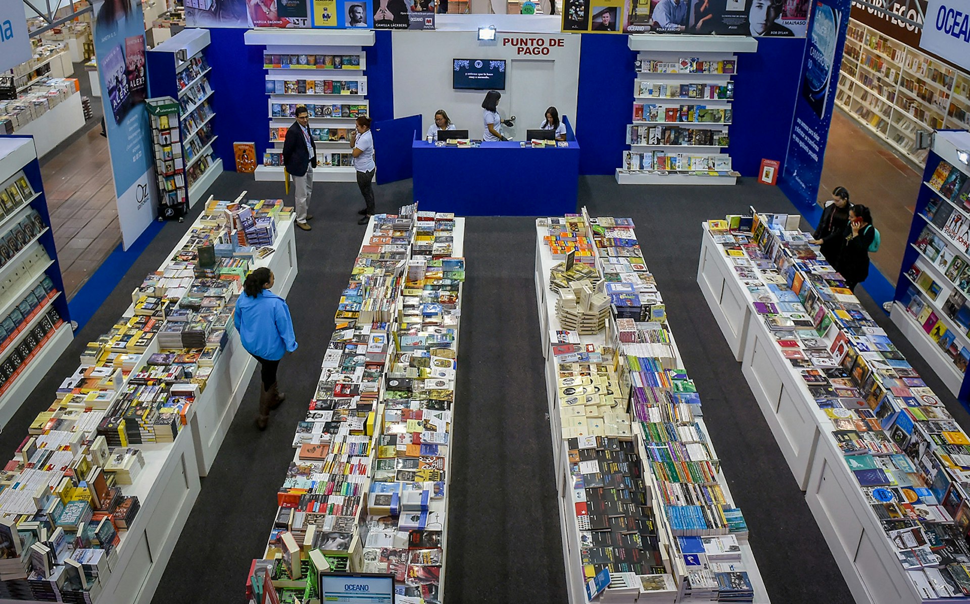 An overhead view of people walking between four tables of books in Bogotá, Colombia