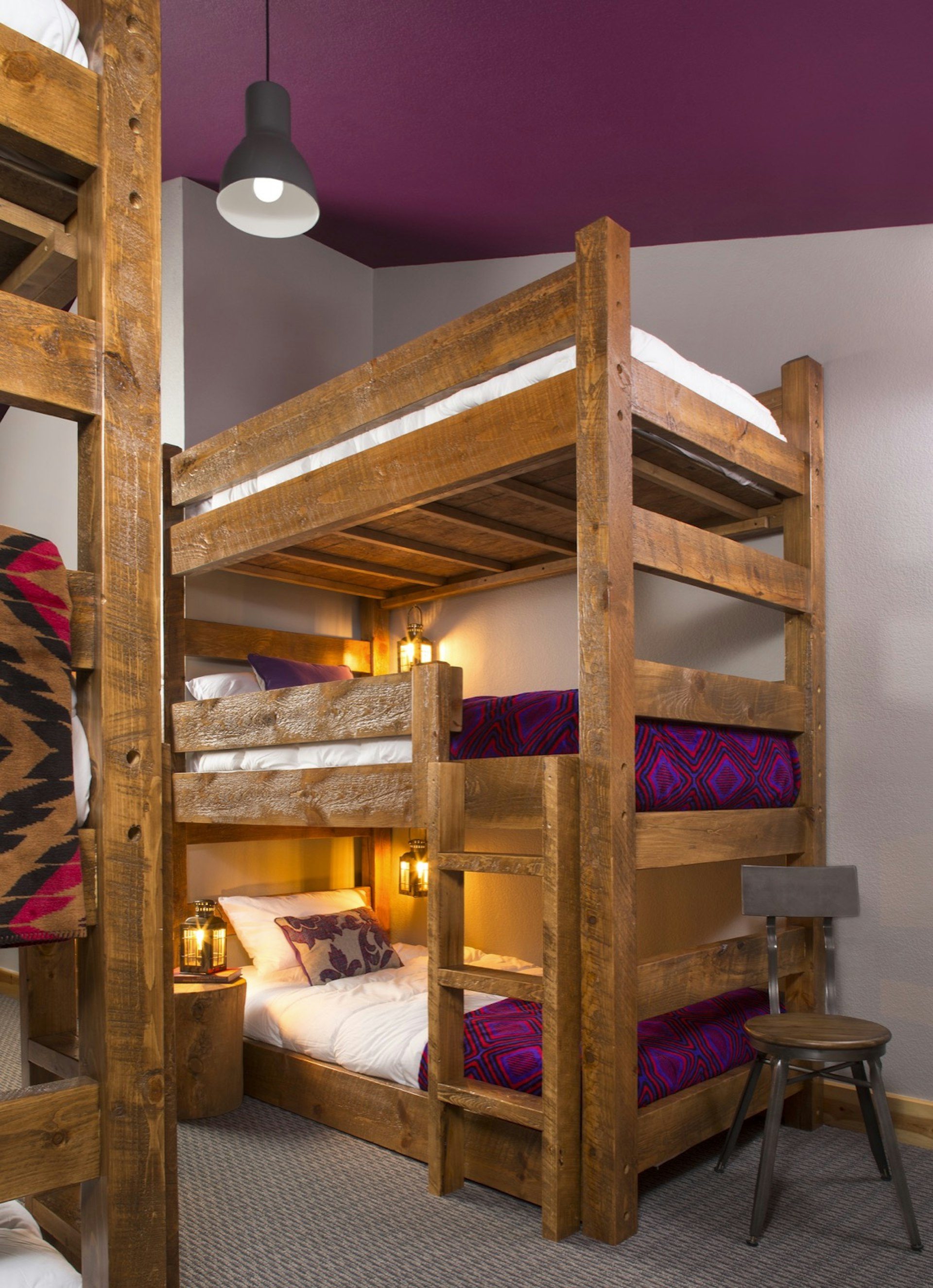 A triple-decker dorm bed, with purple mattresses and a purple ceiling