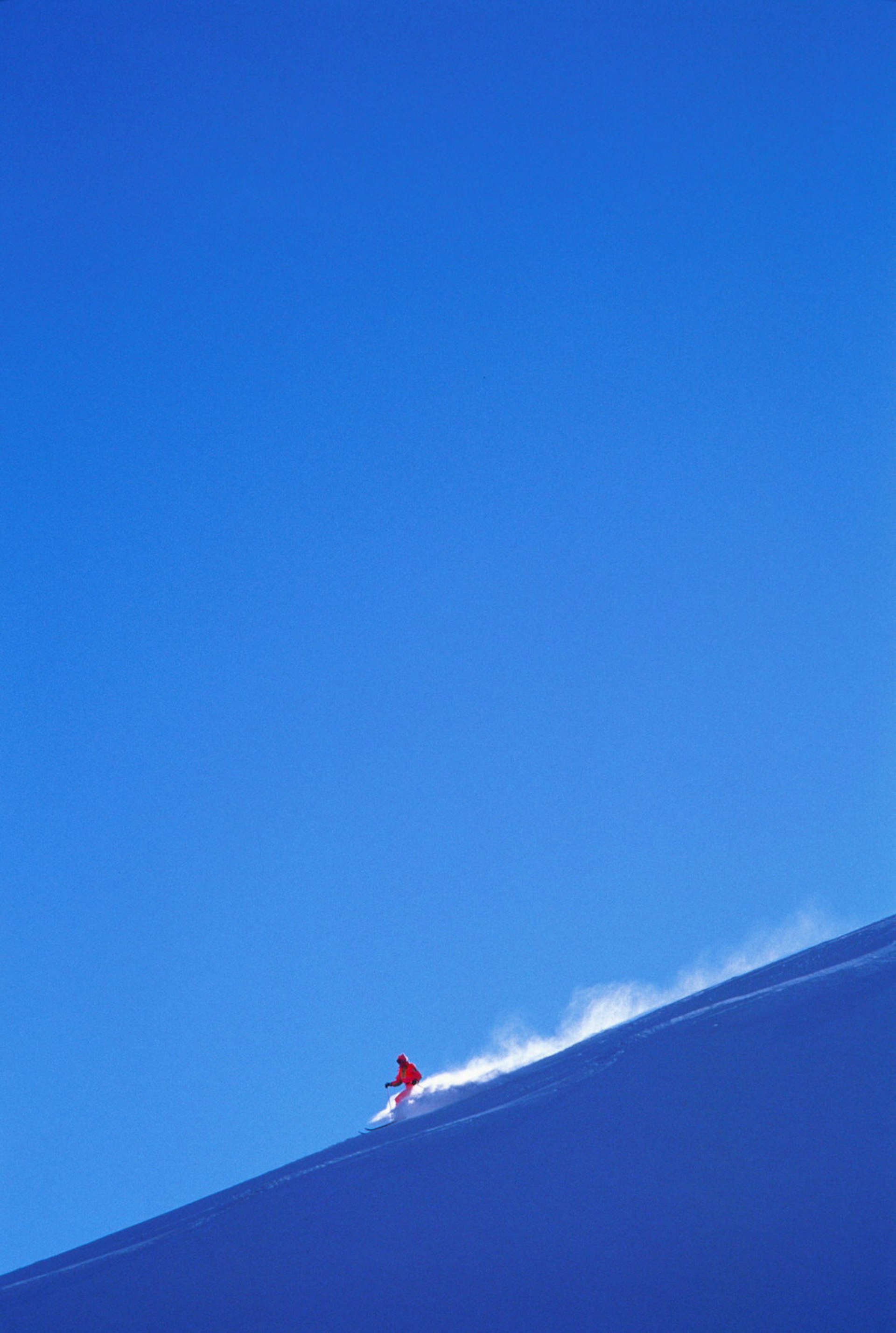 Skier kicks up powder against a blue sky