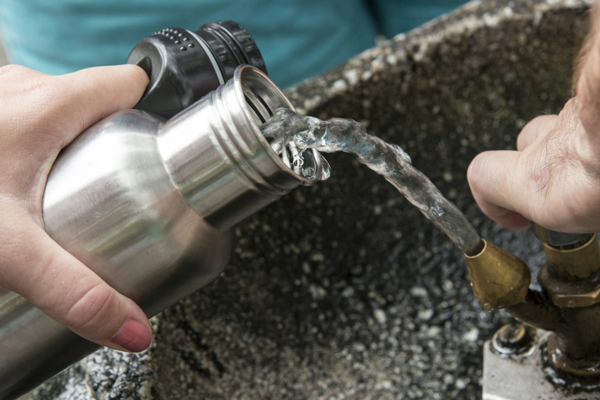 Refilling a reusable tin water bottle at a water fountain