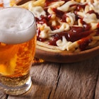 Canadian food: beer and fries with sauce close-up on the table