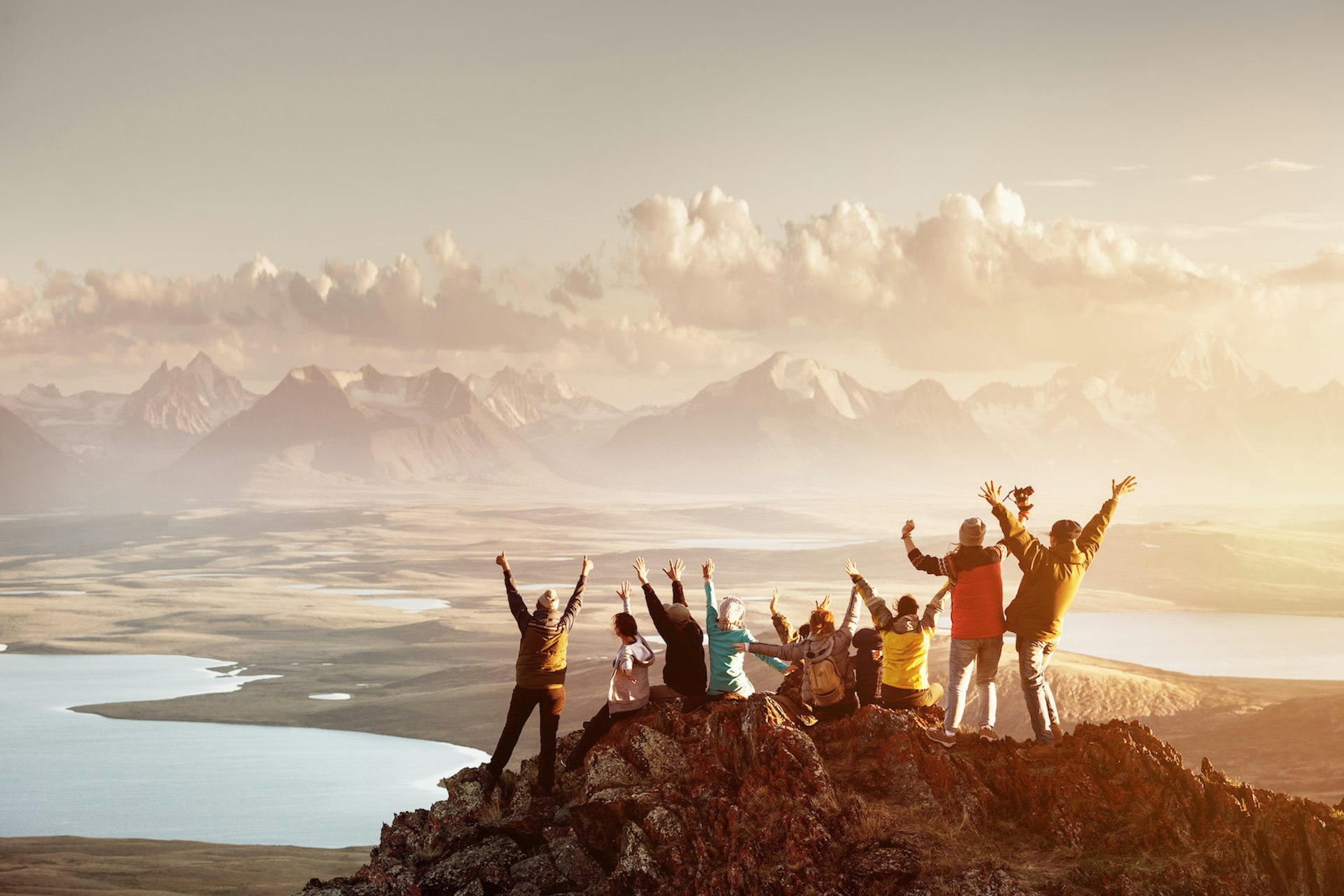 A group of people celebrate on the summit of a mountain