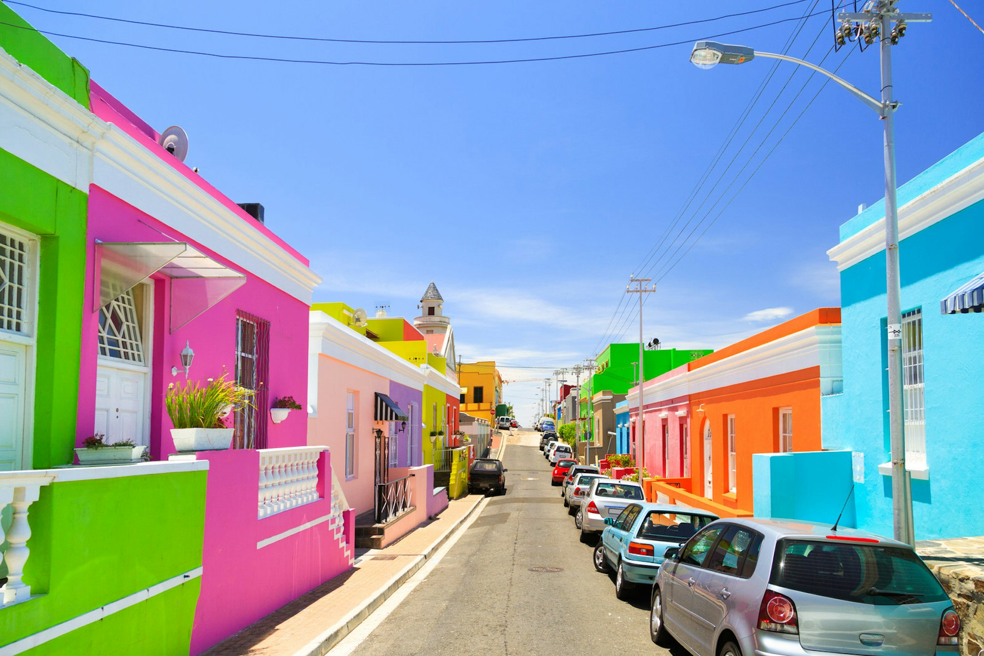 A series of row houses and front walls, each a bright pastel shade of pink, green, orange, yellow and red, flank either side of the street © Nicky Classen / Lonely Planet © espiegle / Getty Images