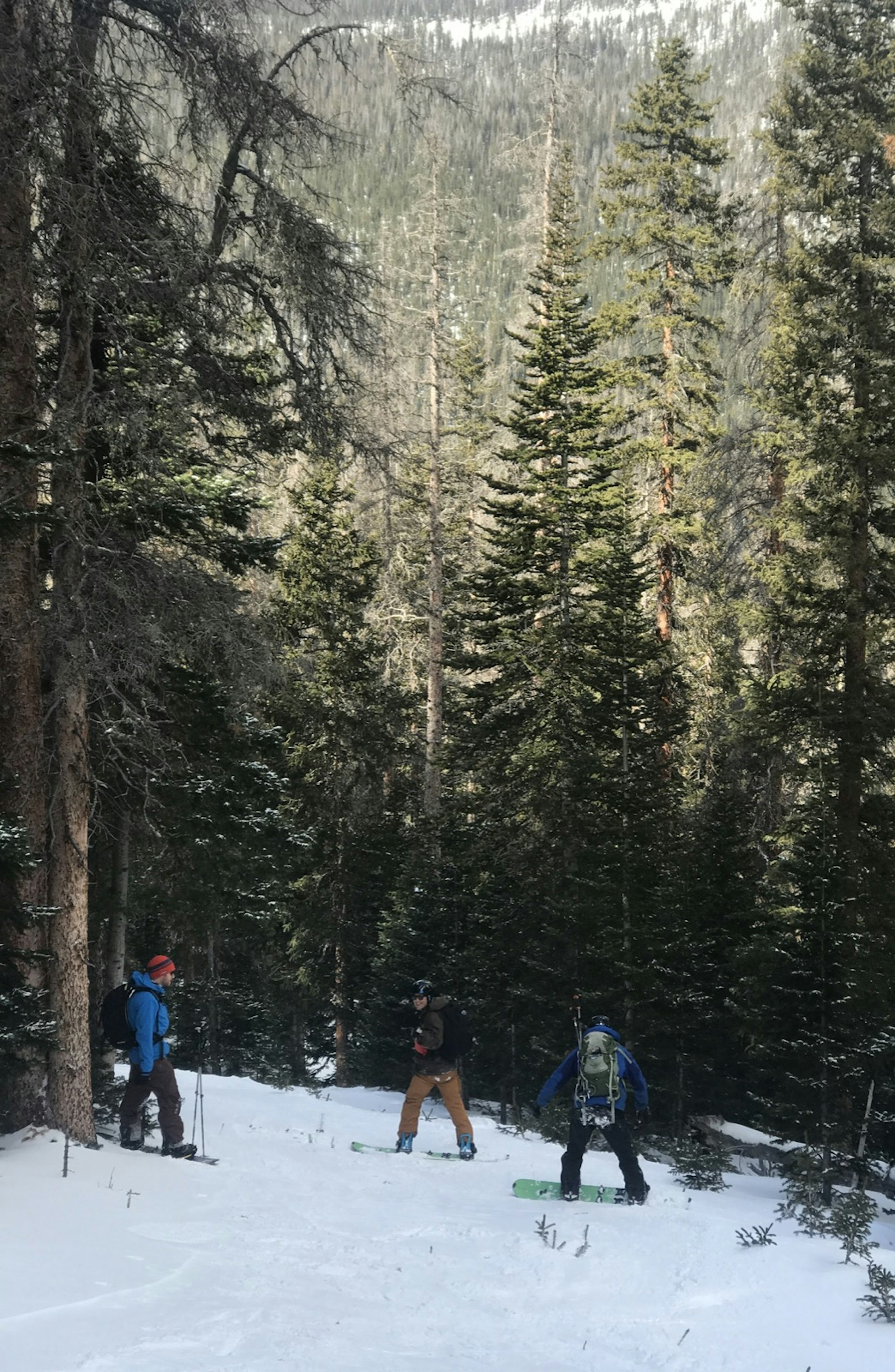 Three men ride down a mountain on splitboards in Rocky Mountain National Park in Colorado