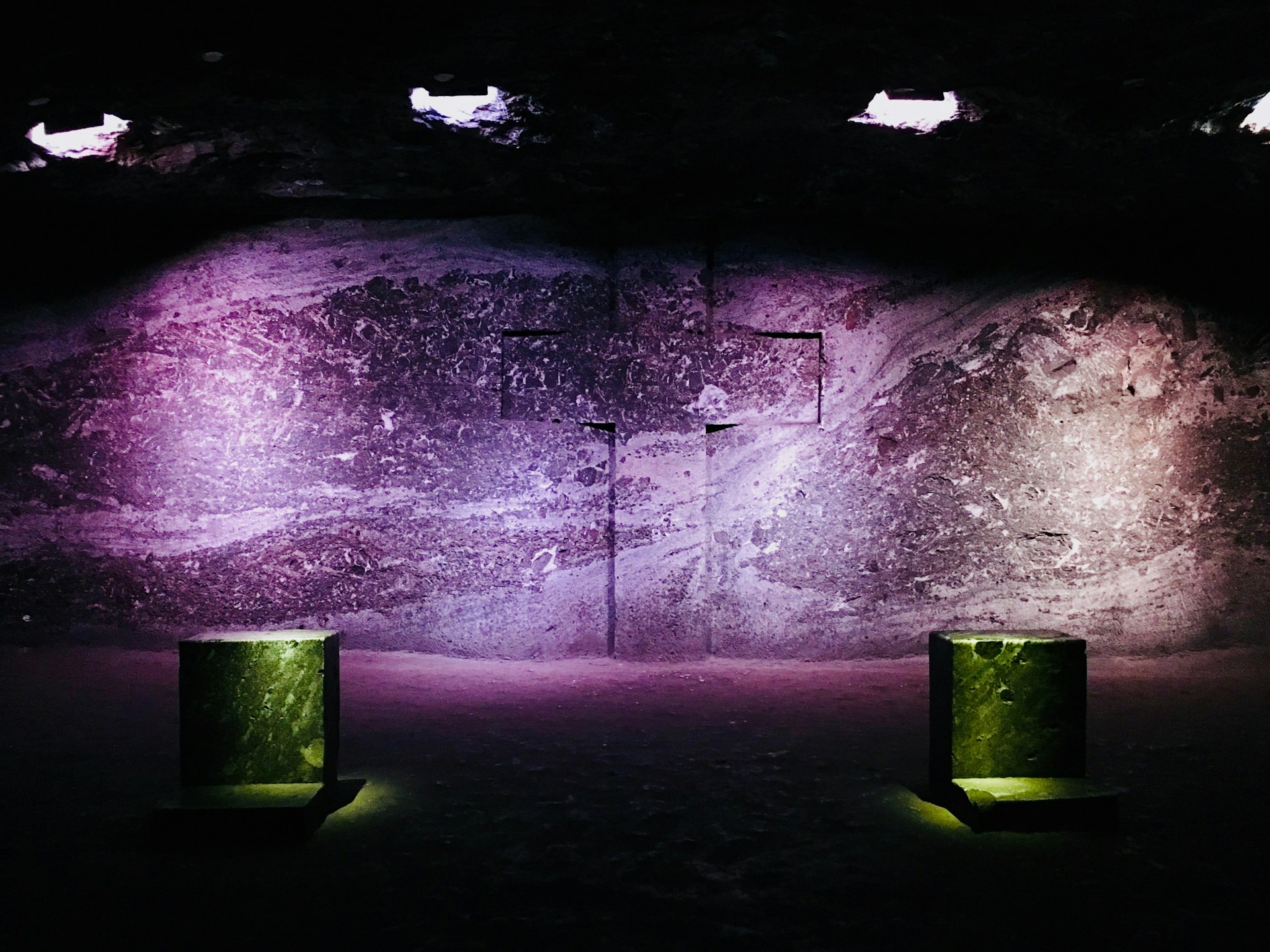 Two stone praying alters frame a large crossed carved into the rock wall of the salt cathedral in Bogotá, Colombia