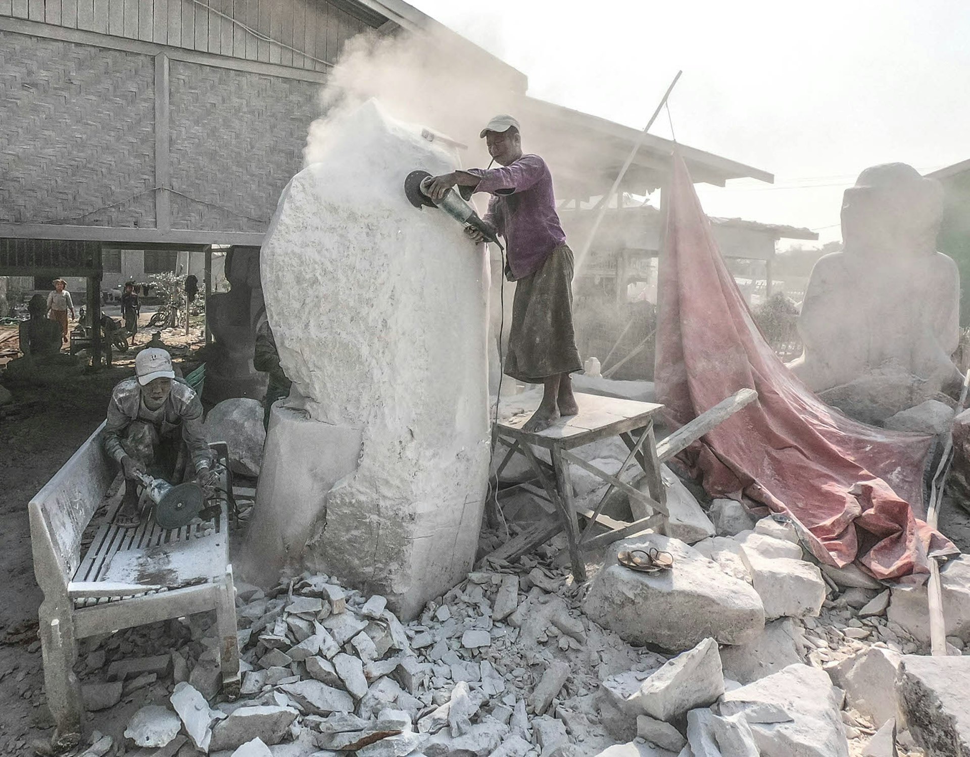 White dust fills the air as workmen sand down a slab of alabaster in Sakyin