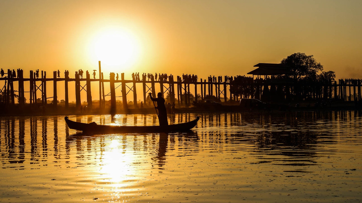 A boatman rows his way past U-Bein bridge at sunset
