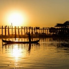 A boatman rows his way past U-Bein bridge at sunset