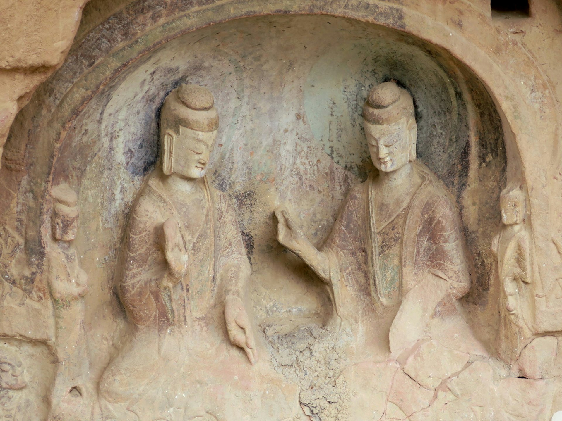 Two seated bodhisattvas are carved into a mud niche, each with one arm raised.